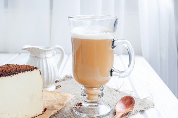 Xícara de café com leite com um pedaço de queijo no café moído