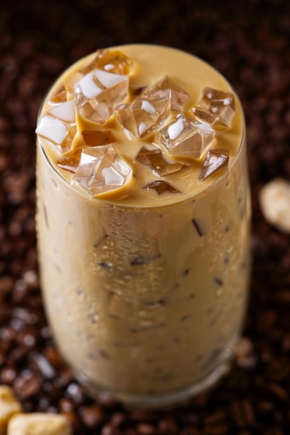 Xícara de café com leite gelado de chá de leite com café com leite gelado em fundo escuro de sementes de café