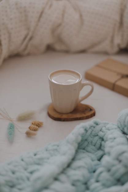 Xícara de café com leite na cama com lençóis brancos e cobertor Café da manhã no conceito de cama