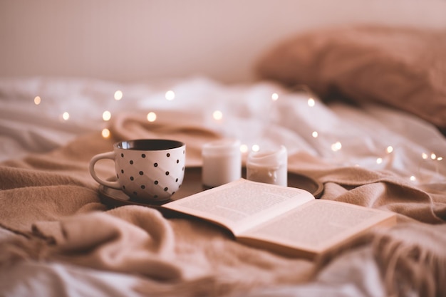 Xícara de café com livro aberto e velas na cama closeup. Estação do outono. Bom Dia. Foco seletivo.