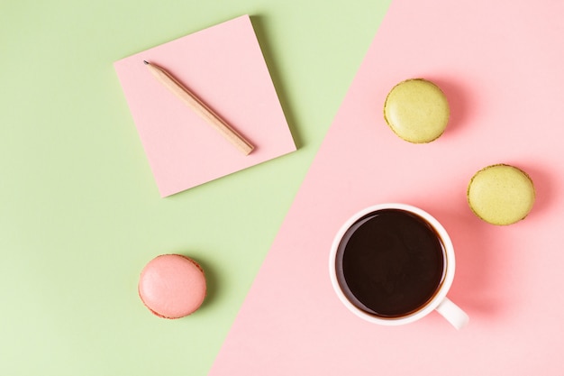 Xícara de café com macaroons em fundo pastel