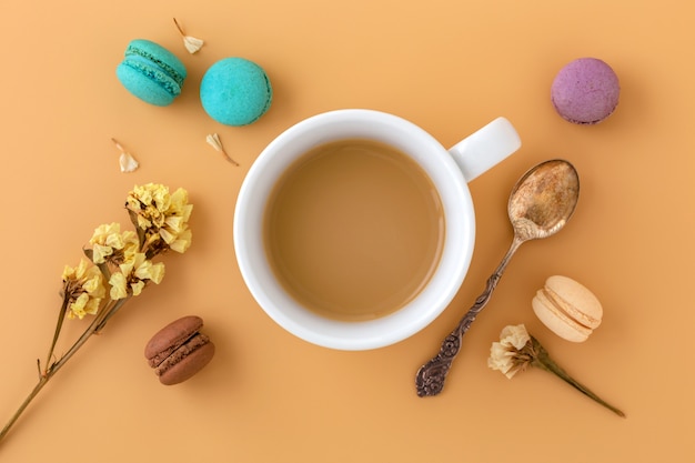 Xícara de café com macaroons, flor e colher vintage, lay plana