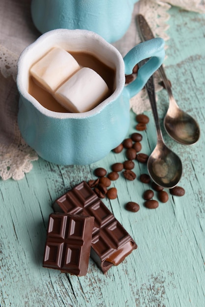 Xícara de café com marshmallow e chocolate na mesa de madeira