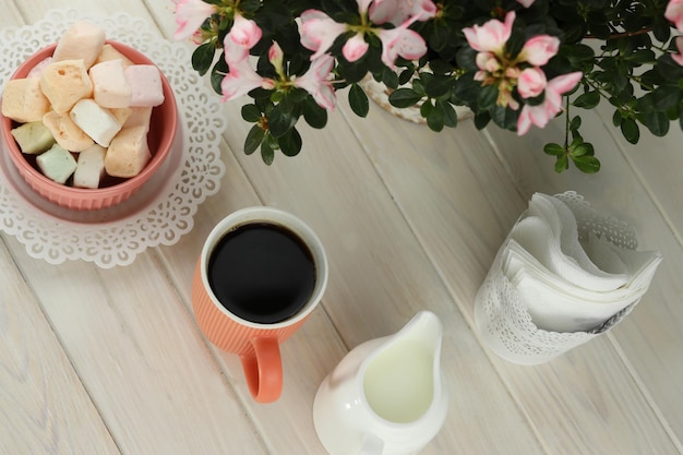 xícara de café com marshmallow na mesa de madeira branca