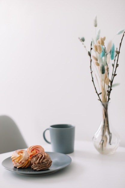 Xícara de café com marshmallows e flores na mesa Manhã romântica