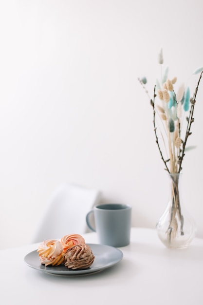 Xícara de café com marshmallows e flores na mesa