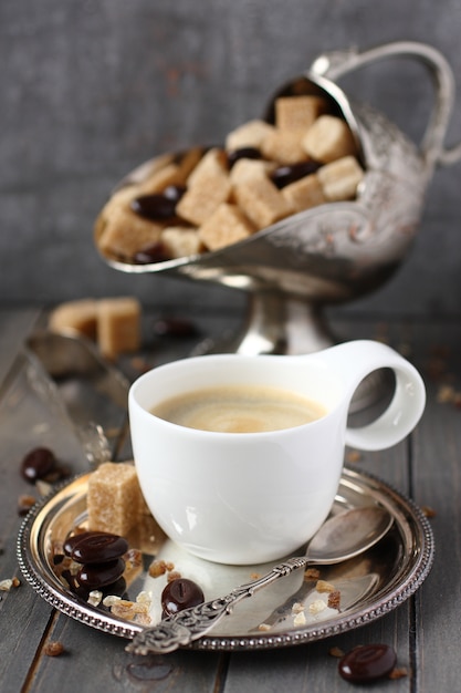 Xícara de café, cubos de açúcar e doces de chocolate no fundo de madeira velho