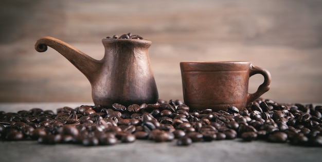 Xícara de café de barro e pote com grãos de café.