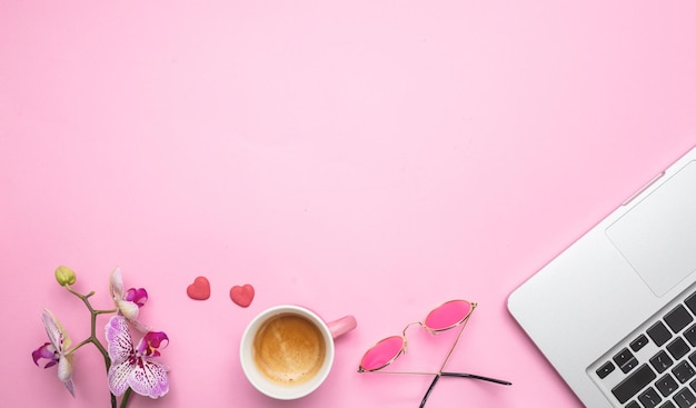 Xícara de café de flores e laptop no espaço de cópia de fundo de mesa rosa