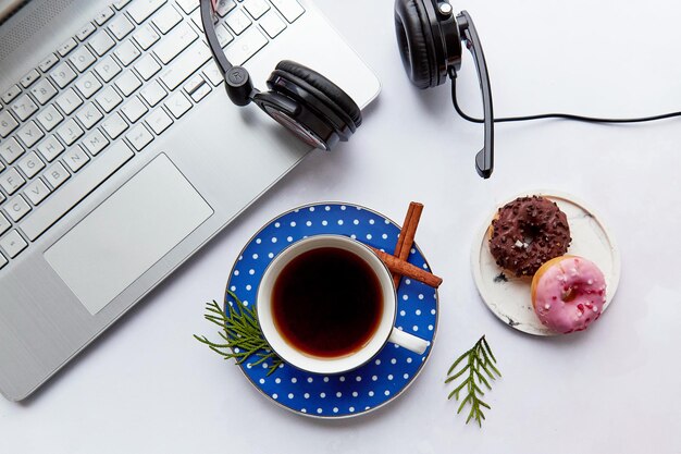 Xícara de café de fones de ouvido para laptop e paus de canela com rosquinhas. Tendo webinar ouvir música