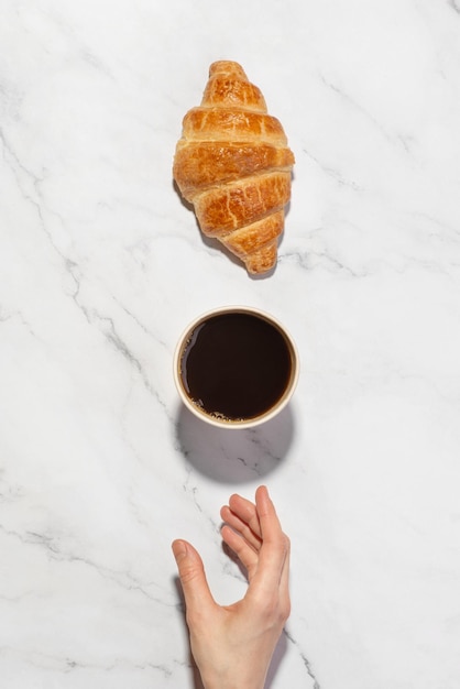 Xícara de café de papel com croissant no fundo branco