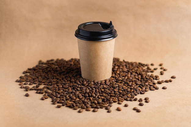 Xícara de café de papel marrom para viagem com tampa preta fica em grãos torrados em fundo marrom Mock up