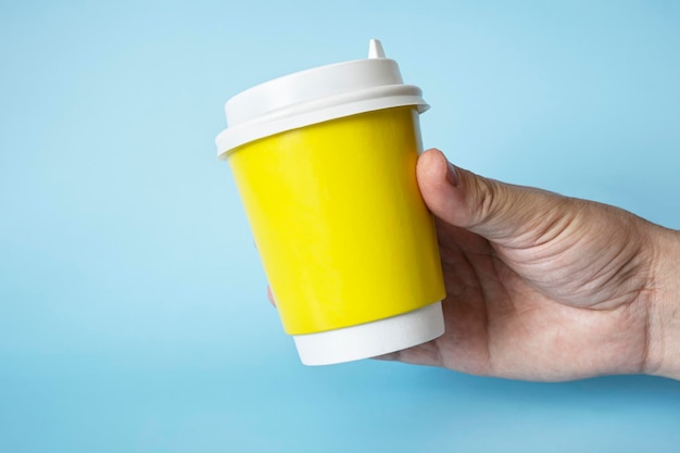 Xícara de café de papel na mão de um homem Xícara de papel para bebida quente Ideia para layout isolado na cor de fundo cor de carne espaço livre para texto