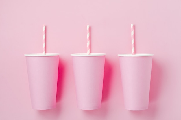 Xícara de café de papel três-de-rosa no fundo claro de papel rosa. Zero conceito de desperdício.