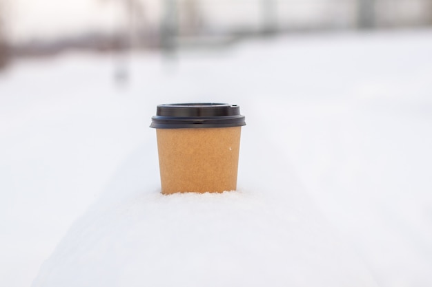 Xícara de café de papelão na neve no inverno. Bebida quente, chá ou café em um copo no inverno lá fora.