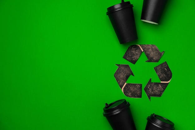 Foto xícara de café descartáveis e placa de reciclagem na vista superior do fundo verde