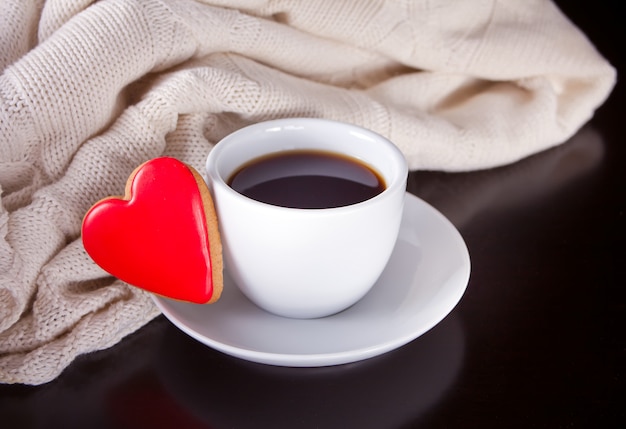 Xícara de café e biscoito em forma de coração na mesa de madeira