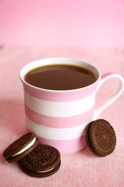 Xícara de café e biscoitos de chocolate com creme na mesa