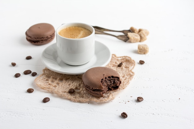 Xícara de café e biscoitos franceses de chocolate nas costas de madeira branca