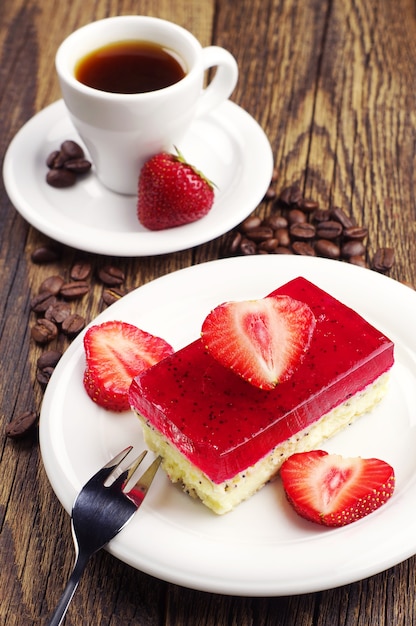 Xícara de café e bolo de morango com papoula na mesa de madeira