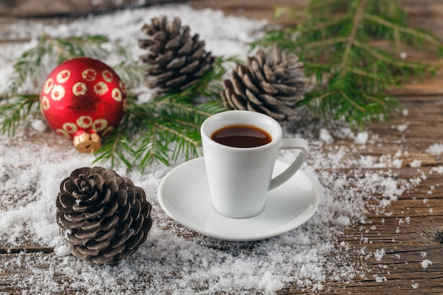 Xícara de café e brinquedos de natal na mesa de madeira.