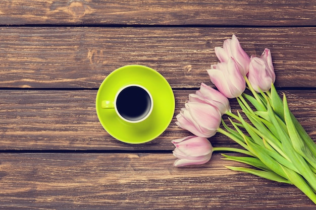 Xícara de café e buquê de tulipas em uma superfície de madeira