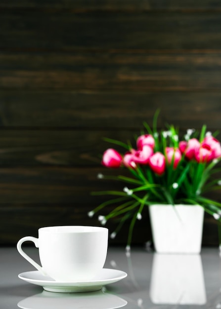 Foto xícara de café e buquê de vaso de flores artificiais na mesa