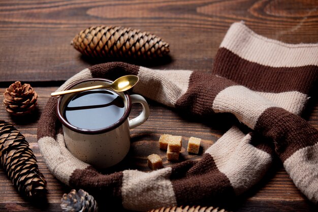 Xícara de café e cachecol na mesa de madeira