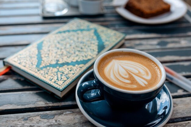 Xícara de café e caderno na mesa no café