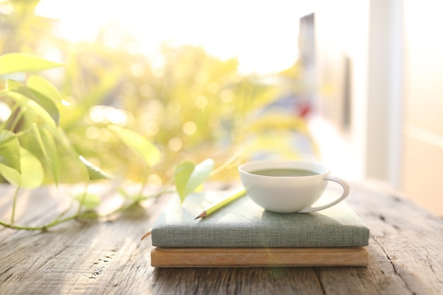 Xícara de café e cadernos e lápis na velha mesa de madeira marrom