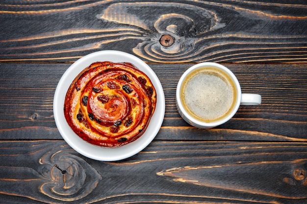 Xícara de café e cinnabon em fundo de madeira