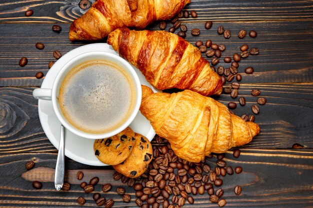 Xícara de café e croissant em fundo de madeira