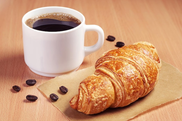 Xícara de café e croissant fresco na mesa