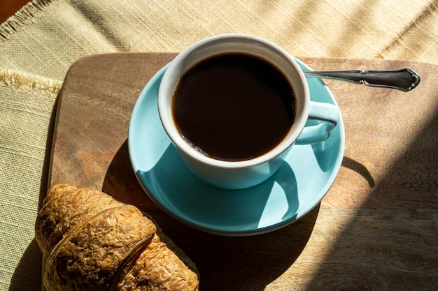 Xícara de café e croissant iluminados pela luz do sol no dia de outono