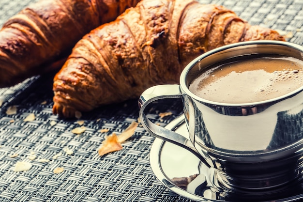 Xícara de café e croissants como menu de café da manhã.