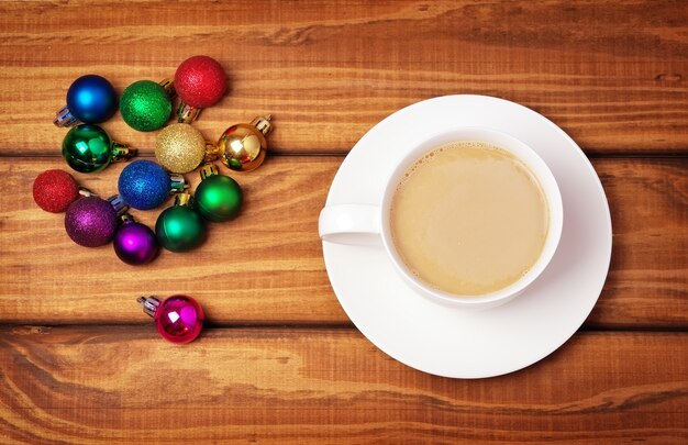 Xícara de café e diferentes bolhas de Natal em fundo de madeira.