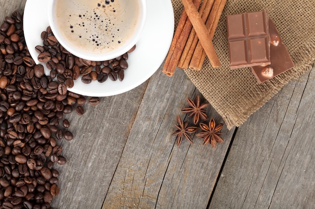 Xícara de café e especiarias na textura da mesa de madeira