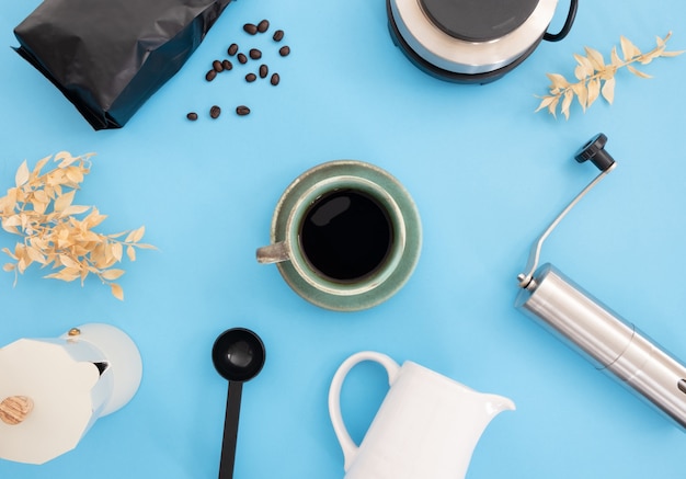 Xícara de café e ferramentas para fazer café em fundo azul claro
