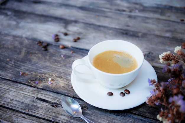 Xícara de café e flor na mesa.