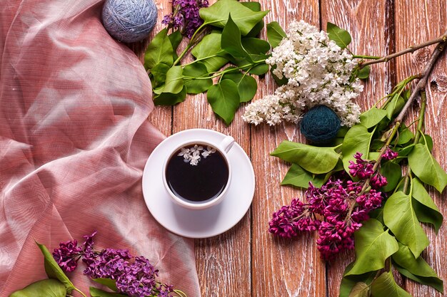Xícara de café e flores lilás coloridas na mesa de madeira do jardim