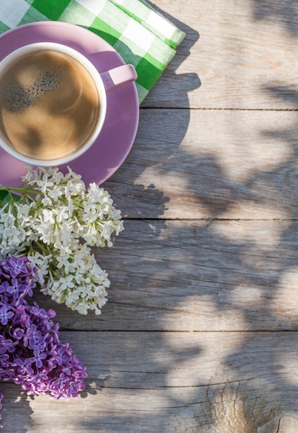 Xícara de café e flores lilás coloridas na mesa do jardim