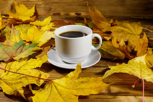 Xícara de café e folhas de bordo de outono na mesa de madeira Conceito de outono