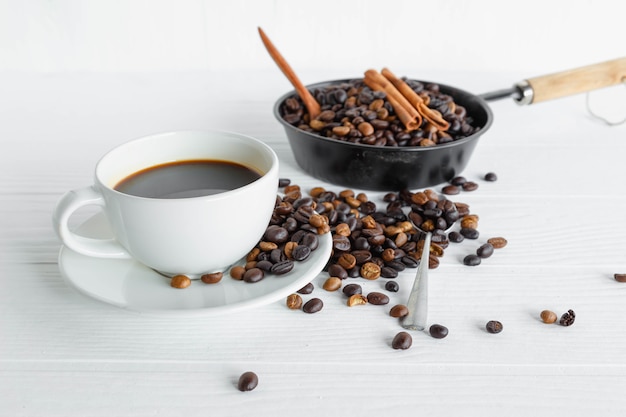 Xícara de café e grão de café na mesa de madeira branca