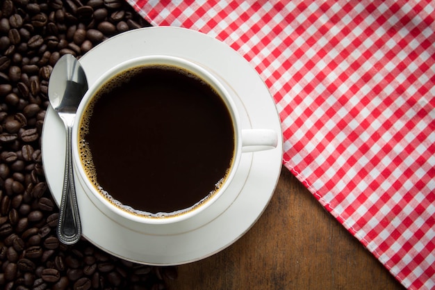 Xícara de café e grãos de café na mesa de madeira