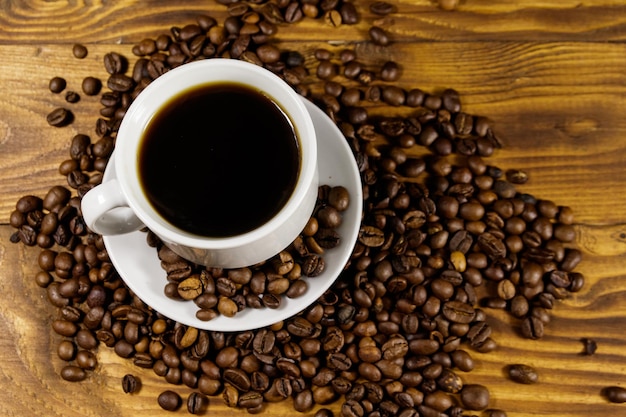 Xícara de café e grãos de café torrados na mesa de madeira. Vista do topo