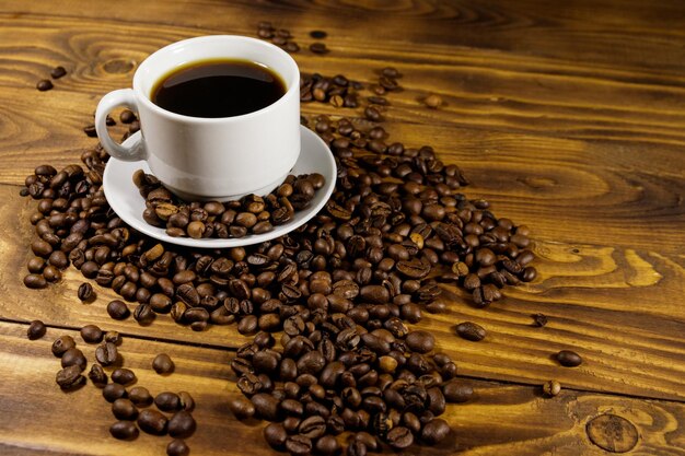 Xícara de café e grãos de café torrados na mesa de madeira