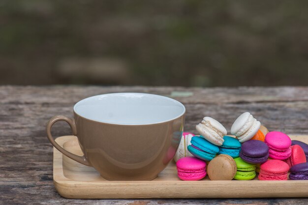 Foto xícara de café e macaroons coloridos no prato na mesa de madeira