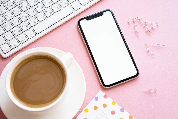 Xícara de café e maquete de smartphone em casa de lady freelancer rosa pastel no local de trabalho