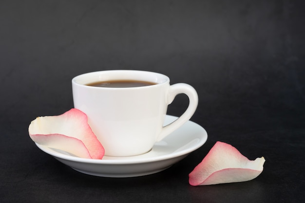 Xícara de café e pétalas de rosa.