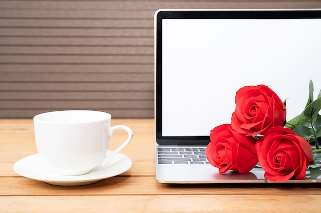 Xícara de café e rosa vermelha com laptop